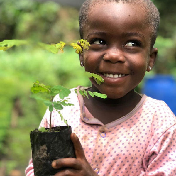 Smiling child holding tree sapling